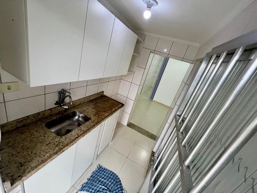 Cozinha uma pia, gabinete e armários brancos.