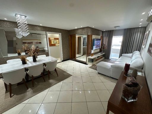 Sala ampla com dois ambientes, parede espelhada, sofá branco e mesa de jantar para seis pessoas.