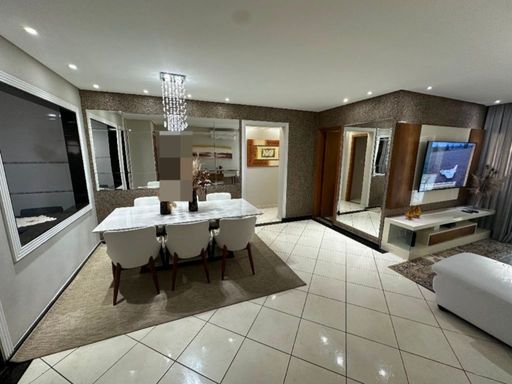 Sala ampla com dois ambientes, parede espelhada, sofá branco e mesa de jantar para seis pessoa