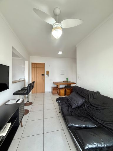 Sala de dois ambientes com mesa de jantar, sofá cama, acesso a sacada gourmet e ventilador de teto.
