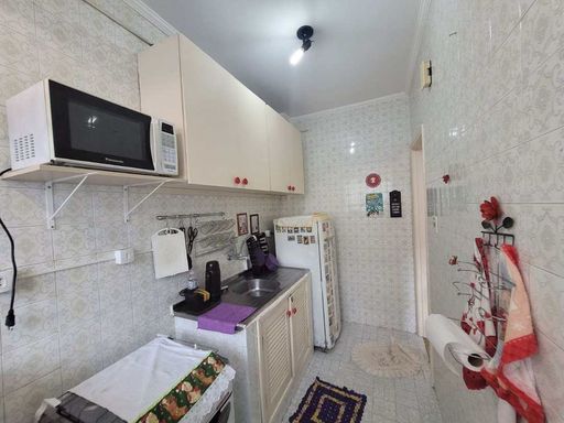 Cozinha com uma geladeira, fogão e armários brancos.