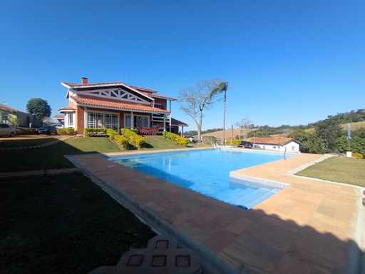 Piscina e deck panorâmico com destaque para a fachada da casa ao fundo.