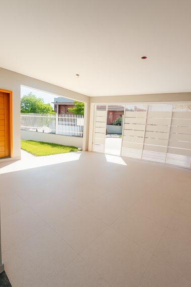 Garagem coberta com acabamento em piso cerâmico e acesso à entrada principal