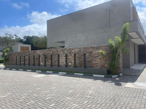 Imponente fachada moderna com paisagismo exuberante e entrada principal.