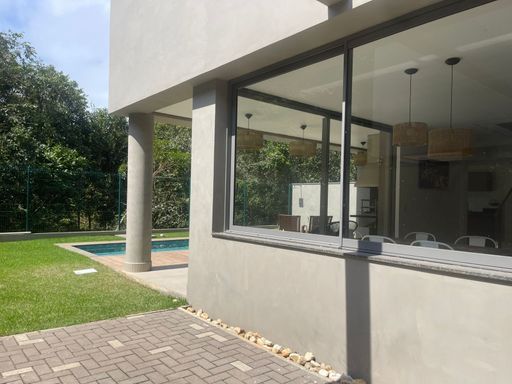 O paisagismo ao redor da piscina e churrasqueira, criando um ambiente verde.