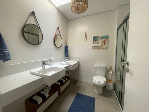 O banheiro da suíte master, com pias duplas e acabamento premium.