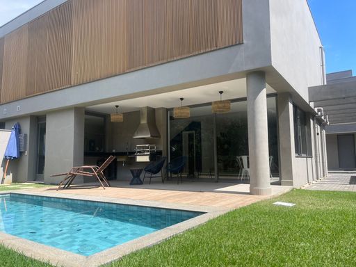 Detalhe da piscina com deck de madeira e espreguiçadeiras.